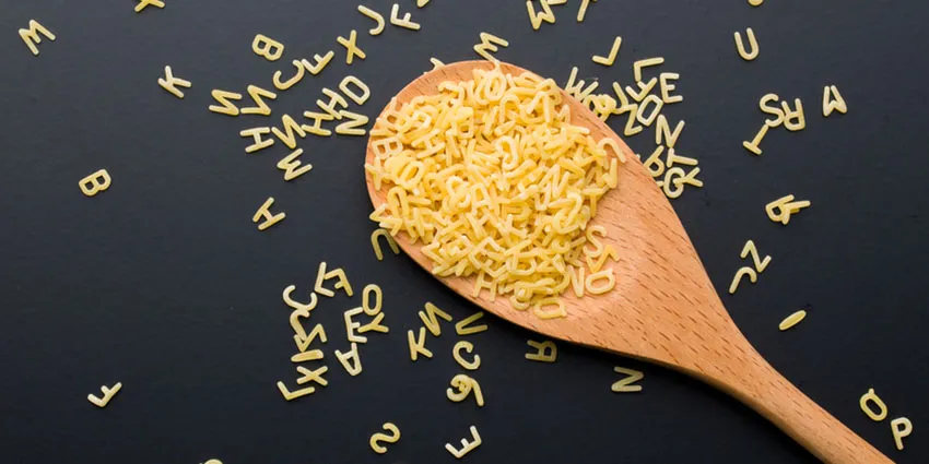 An image of a wooden spoon scooping up alphabet pasta.